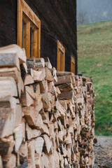 A pile of firewood lies near a wooden house.