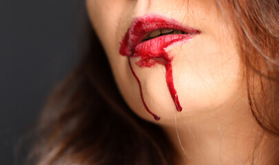 Close up of a woman's lips with blood dripping from her mouth
