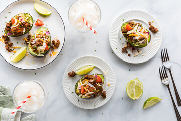 Avocado boats filled with guacamole and topped with taco style fixings.