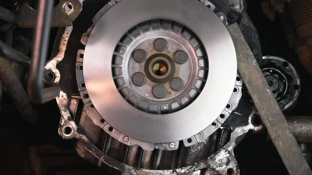 The mechanic's hands install the clutch disc on the engine.