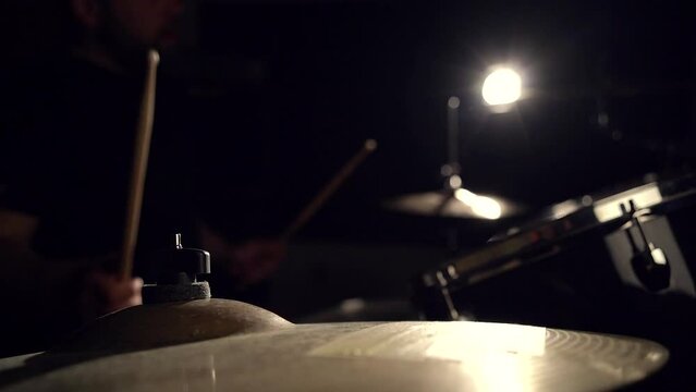 Musician drummer playing hitting drums and cymbals, drumstick close-up view.