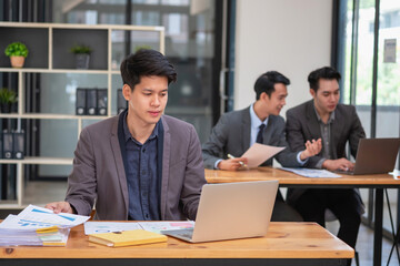 Asian business team consists of marketing staff. accountant and financial officer Help each other analyze company profits using tablets. calculator Laptop computers, graph paper, and corporate pens.