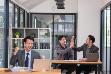 Portrait of an Asian business team showing great joy and happiness celebrating positive success in business concept.