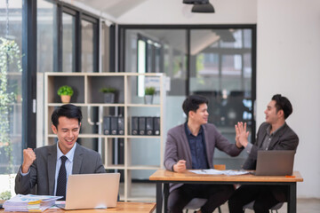 Portrait of an Asian business team showing great joy and happiness celebrating positive success in business concept.