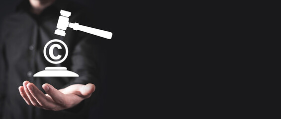Male hand showing judge gavel with a Copyright symbol.