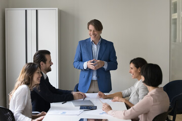 Happy mature boss gives presentation for clients in conference room. Business trainer lead training, professional seminar for staff gather in boardroom feel satisfied with work results, sales growth