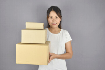 Asian woman smiling holding package box on grey background. Delivery and customer services concept.