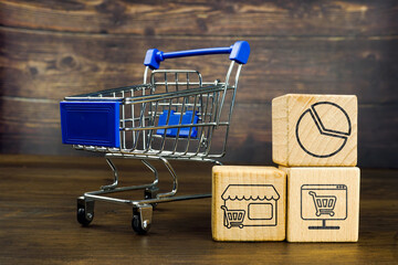 Wooden cubes and shopping cart. Shopping online or offline concept.