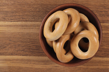 Dry bagels in a bowl on a wooden background, top view. Copy space for text
