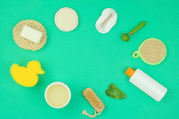 Washcloths, cream, shampoo, gua sha and other accessories in green background. Top view. Copy space for text.