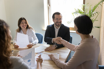 Confident businessman gather for negotiations in modern office with business partner, sit at desk...