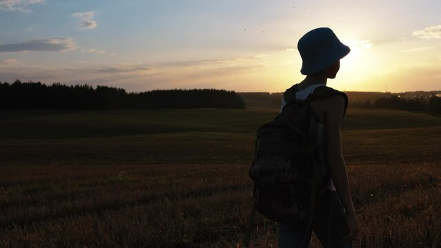 Wanderlust Adventure: Teen Boy Walking Across Summer Field at Sunset with Backpack, Steadicam Shot