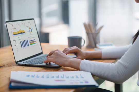Businesswoman accountant using a graphs and charts to analyze market data, balance sheets,accounts,and net profits in order to plan new sales strategies and increase production capacity.