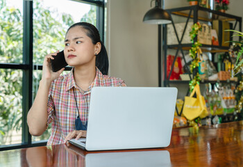 Young Asian woman sitting at a desk talking on a smartphone looks tense, worried, listening to bad news, and feeling hopeless. Received an unsatisfactory response on the phone. problems at work.