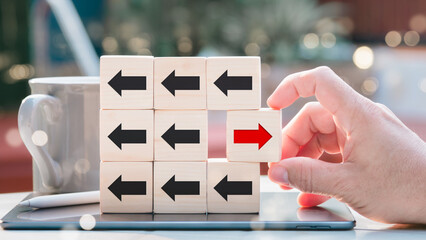 Concept of a wooden block with a red arrow pointing in one way and a black arrow pointing in the...