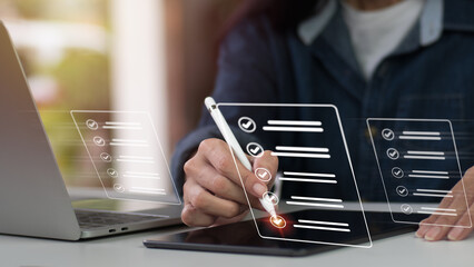 Concept of a company performance checklist, with a businesswoman completing a digital form checklist while using a laptop and tablet.