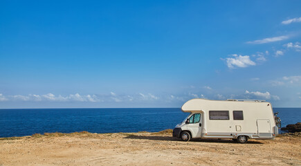 Camper rv caravan on mediterranean coast in Italy. Wild camping on sea shore.