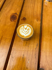 Hot coffee latte on glass at wooden table.