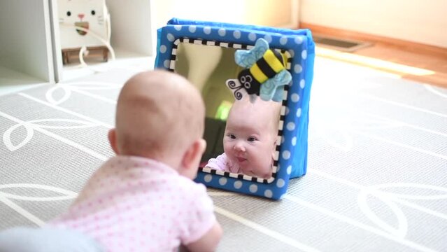 Baby looking in the mirror during tummy time. Baby development stages. 