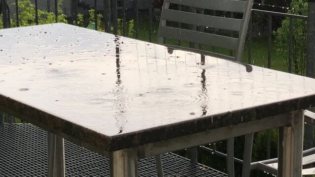 
raindrops splashing on a desk on a balcony