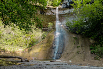 La cascade du Pain de Sucre est une imposante stalagmite de tuf de 20 mètres de haut dont la pointe est arrondie par la cascade de la Vézeronce qui l'arrose à Surjoux dans l'Ain - obrazy, fototapety, plakaty