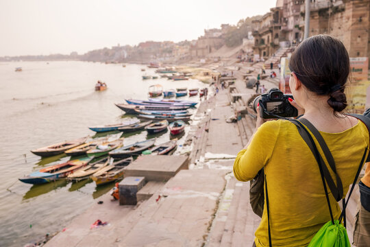 A tourist woman takes pictures of boats on the Ganges River in Varanasi.