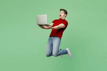 Full body fun surprised shocked young brunet IT man he wears red t-shirt casual clothes jump high...