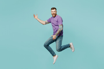 Full body singer excited happy young man he wears purple t-shirt jump high pov playing guitar, do hand gesture isolated on plain pastel light blue cyan background studio portrait. Lifestyle concept. - obrazy, fototapety, plakaty