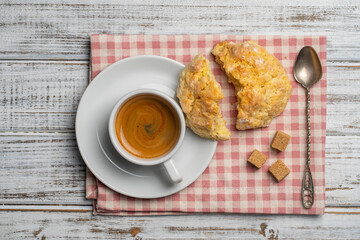 White porcelain coffee cup with saucer and lemon cookies on a wooden table, closeup, top view. Hot coffee in a breakfast