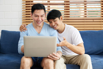 LGBT gay couple using laptop computer on sofa