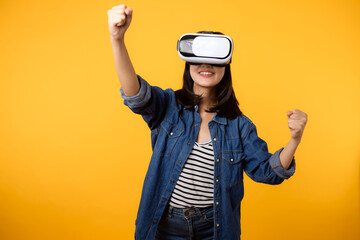 Young asian woman happy success wearing virtual reality headset game entertainment isolated on yellow background. Winner of cyber future video game concept.