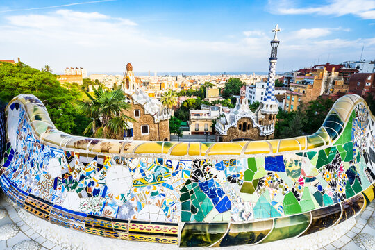 Barcelona, seen from Park G&uuml;ell with colorful mosaics set against a backdrop of clouds and blue sky.