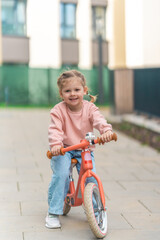 Little girl riding balance bike in the courtyard of the residence in Prague, Europe