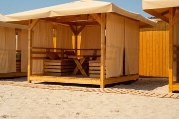 Arbor wooden bungalow in the open air. Cafe on the sandy beach. Vacation on the coast.