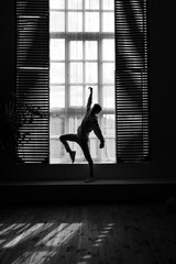 Full length image of a dancer in position , posing near window. Black and white photo.
