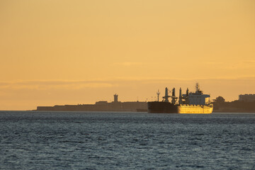 Obraz premium An industrial ship sails down the river at sunset