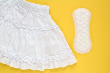 White skirt and woman sanitary pad on yellow background. Female menstruation cycle period. Hygiene concept. Linen and health protection idea. Copy space