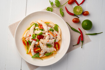 Thai Spicy Squid Salad,mixed squid with onion and tomato in chilli lime sauce in white plate.Thai food.Top view