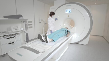 The doctor performs an MRI scan for a patient at the clinic. The girl lies in the MRI device....