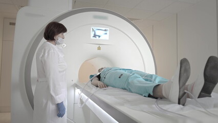 Doctor makes an MRI scan for a patient in a clinic. The girl lies in the MRI device. Magnetic...