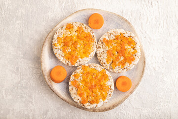 Carrot jam with puffed rice cakes on gray concrete. Top view.