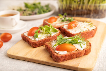 Red beet bread sandwiches with cream cheese, tomatoes and microgreen on gray. side view, selective focus.