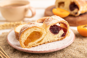 Homemade sweet bun with apricot jam on white wooden. side view, selective focus.