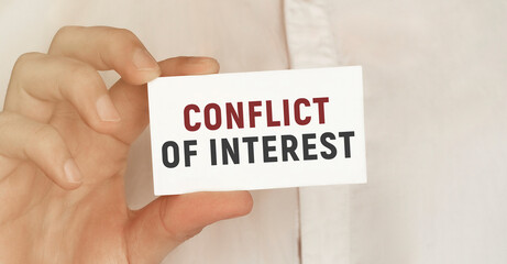 Card with text Conflict of interest in a man's hand