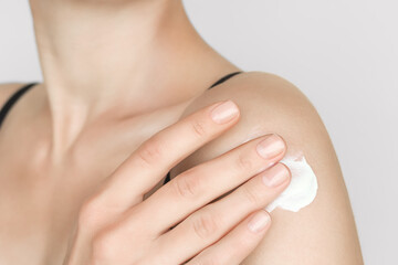 a woman applies sunscreen on the skin of her shoulder. skin care, skin protection concept