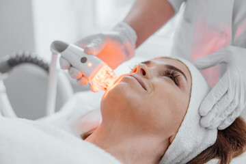 Photo using LED therapy, taken in a dermatological clinic. Light therapy accelerates healing and improves skin condition by reducing lines and wrinkles. Girl at the cosmetologist on the procedure