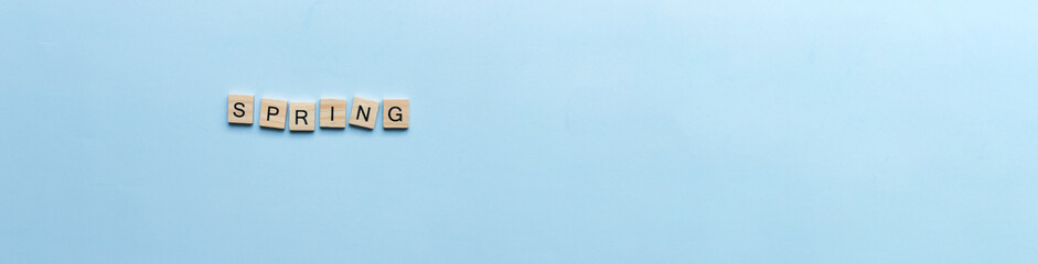 Banner The word spring laid out in wooden letters. Flat lay spring on blue background