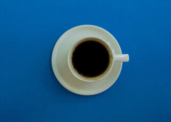 Cup of coffee on a blue background, top view.