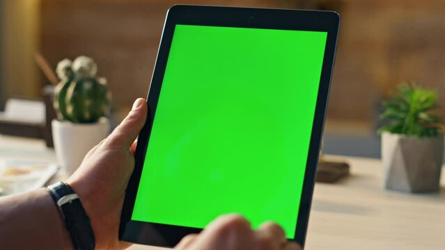 Hand scrolling greenscreen tablet searching information in home office close up