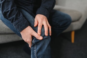 Fototapeta premium people, health care and problem concept - unhappy senior man suffering from knee ache at home